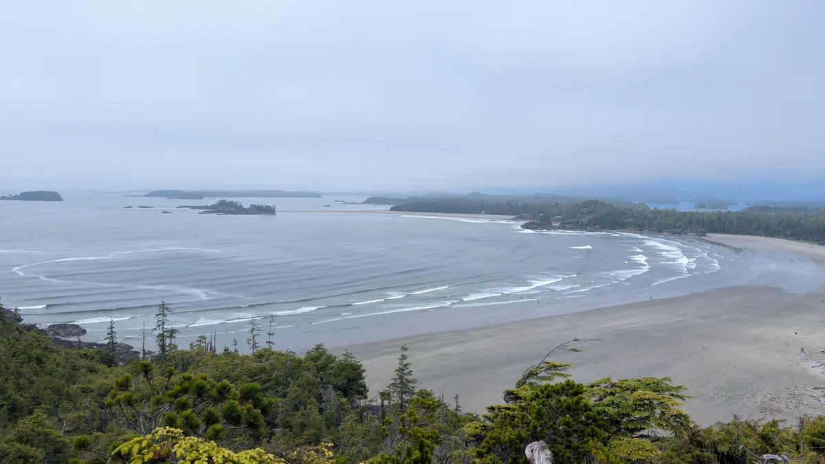 Cox Bay from the lookout above: a curve of sand, lines of surf and islands offshore