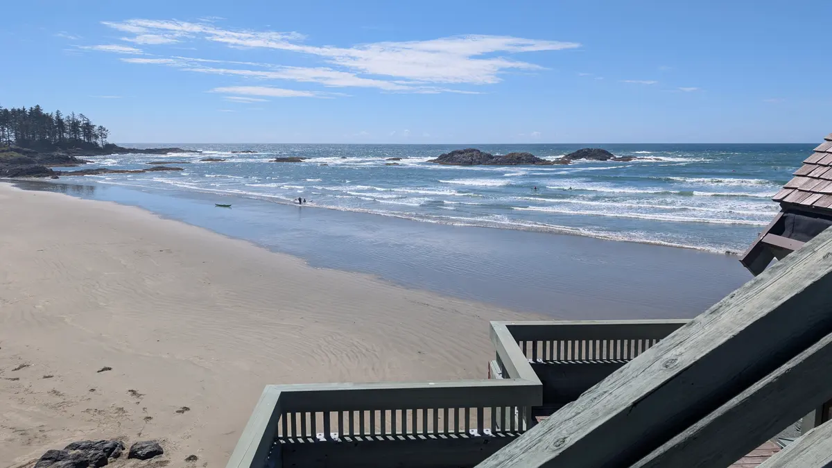 Looking down from wooden steps onto the sand and surf at Wickaninnish Beach