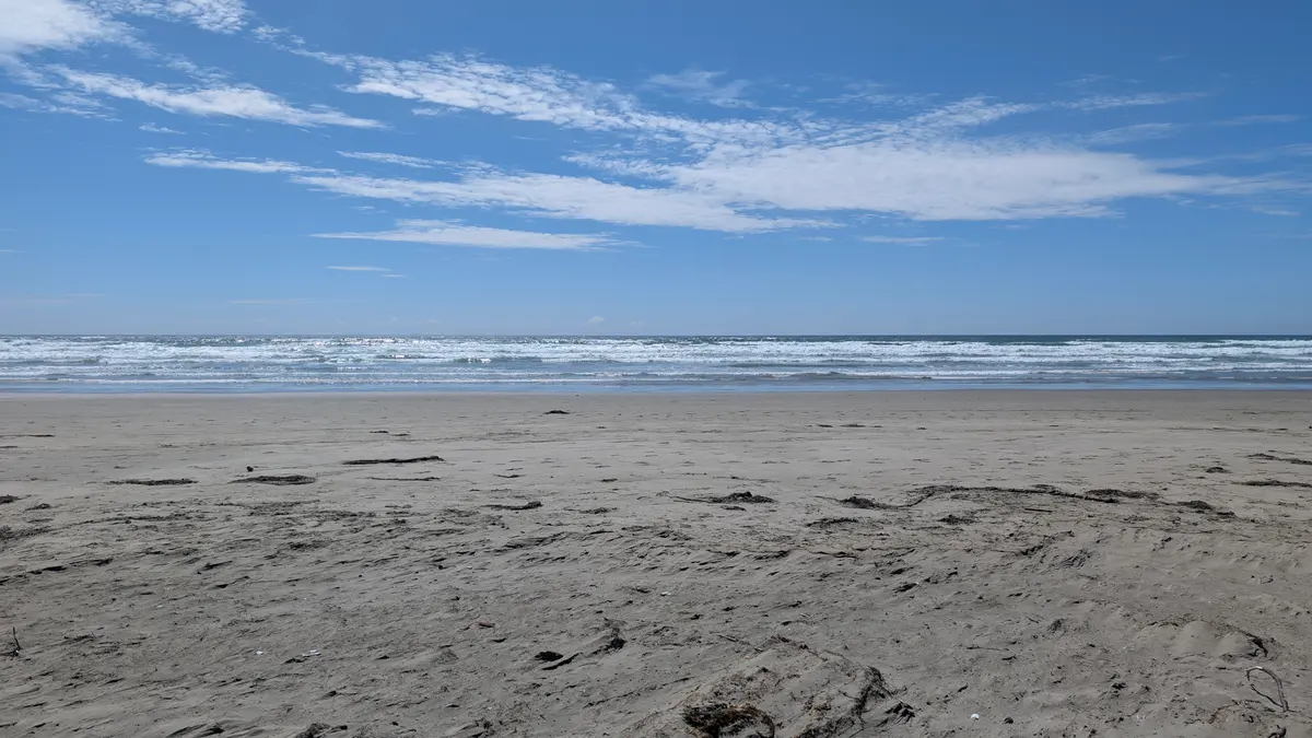 Flat sand and rolling surf under a blue sky at Wickaninnish Beach